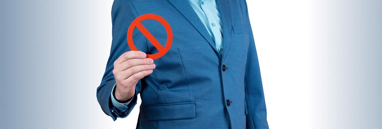 Man holding a sign with a cross mark